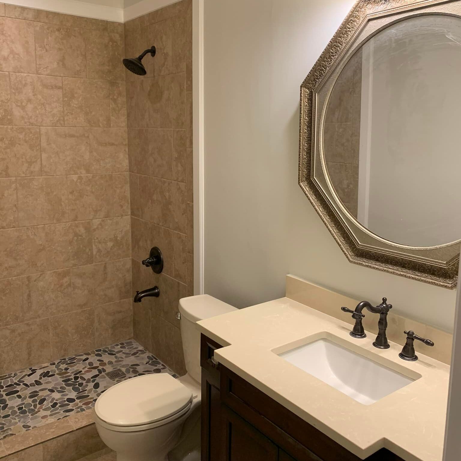 Tan tiled shower with stone floor